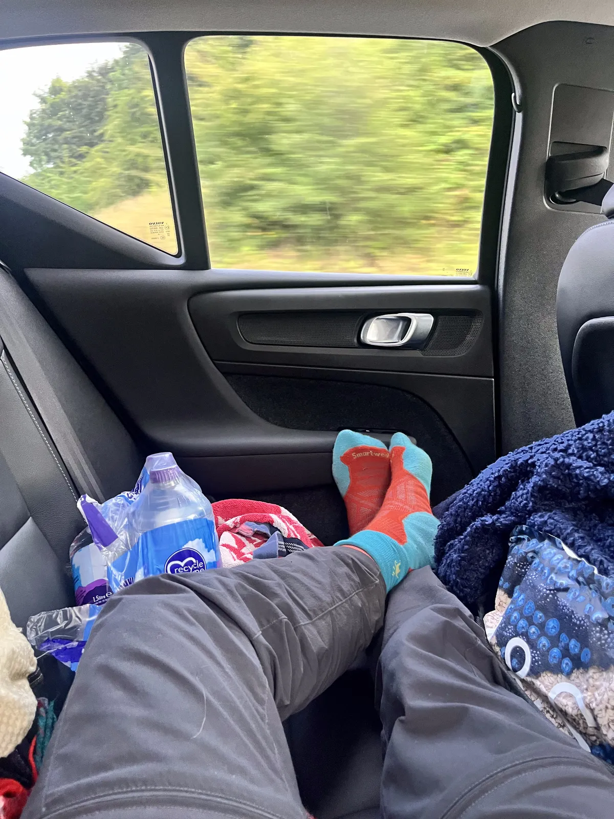The back seat of the XC40 between mountains. Boots off, feet up, Smartwool socks on show.