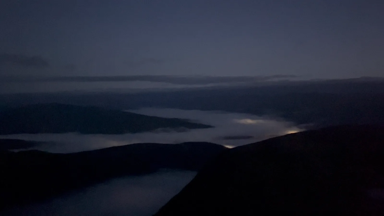 Above the fog on Ben Nevis within the first hour, the valley lights still glowing underneath it.